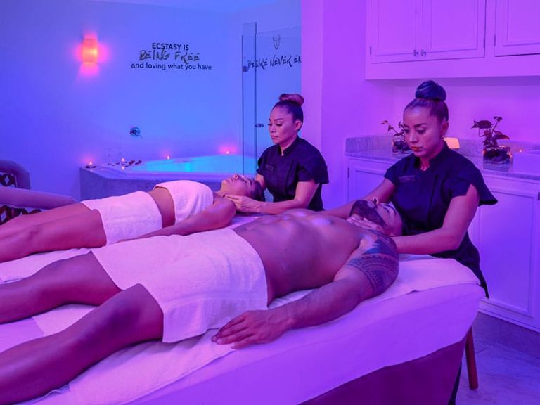 a group of people lying on a bed in a room with purple lighting