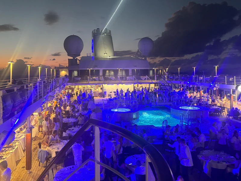 Guests gathered around the illuminated pool deck on an earlier Desire Caribbean cruise