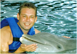 A man in a life jacket beside a dolphin in the water