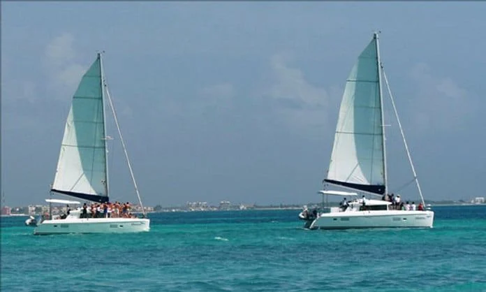 Two catamarans sailing in turquoise water off Cancun