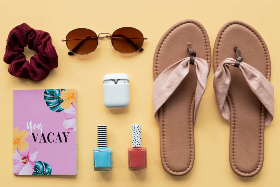 Sandals, sunglasses and small travel essentials laid out ready for a beach holiday