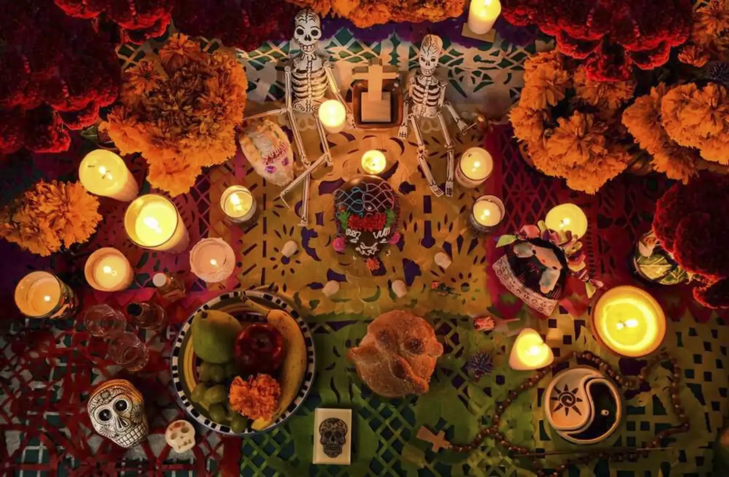 Day of the Dead altar with marigolds, candles, skeleton figures and pan de muerto
