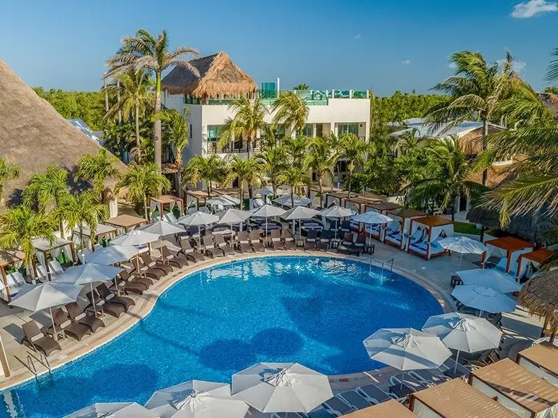 Aerial view of the Desire Riviera Maya pool lined with loungers and palms