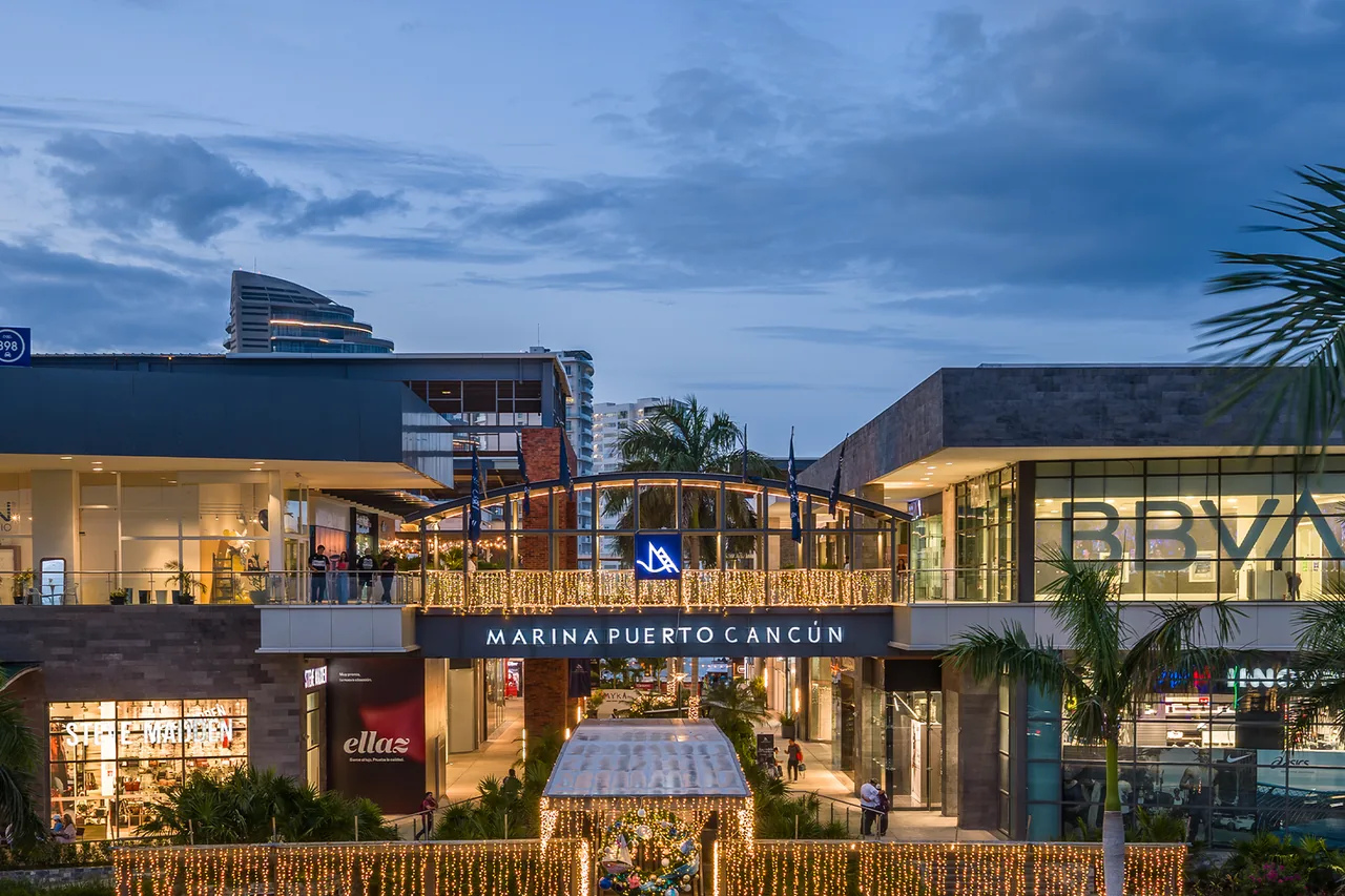 Marina Puerto Cancun shopping centre entrance and illuminated shops at dusk