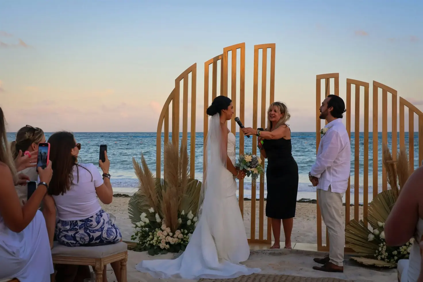 Los novios junto a su oficiante durante una ceremonia de boda en la playa en Cancún.