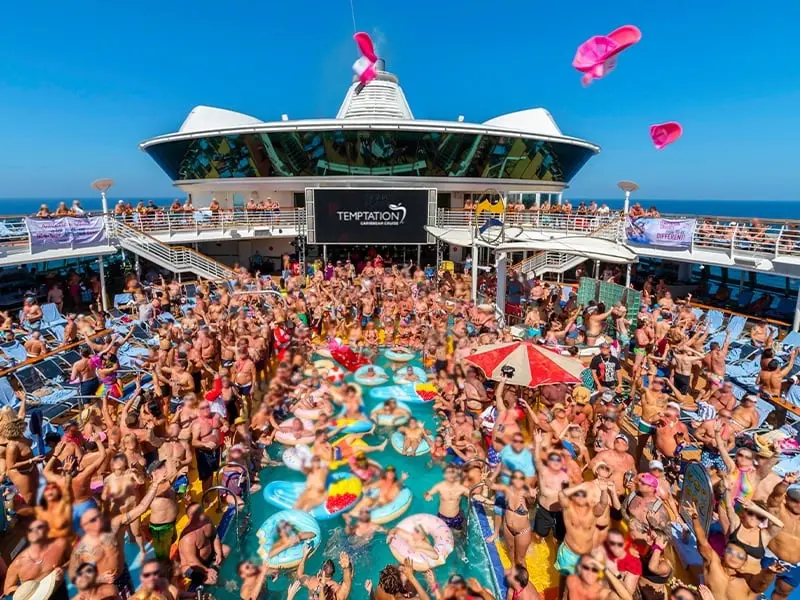 Huéspedes disfrutando de una fiesta en la piscina durante el día en un crucero Temptation anterior.