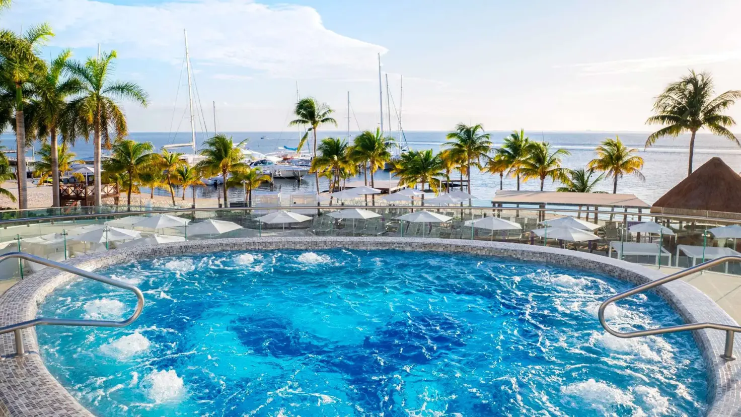 The Jacuzzi at Bash at Temptation Cancun Resort, with palm trees and the sea beyond