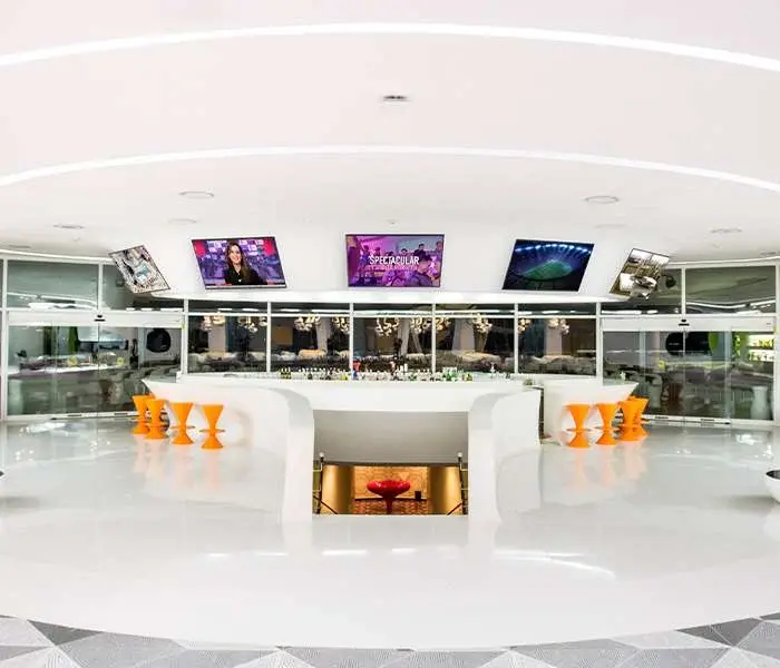 Level 3.5 lobby bar with white seating, orange stools and televisions