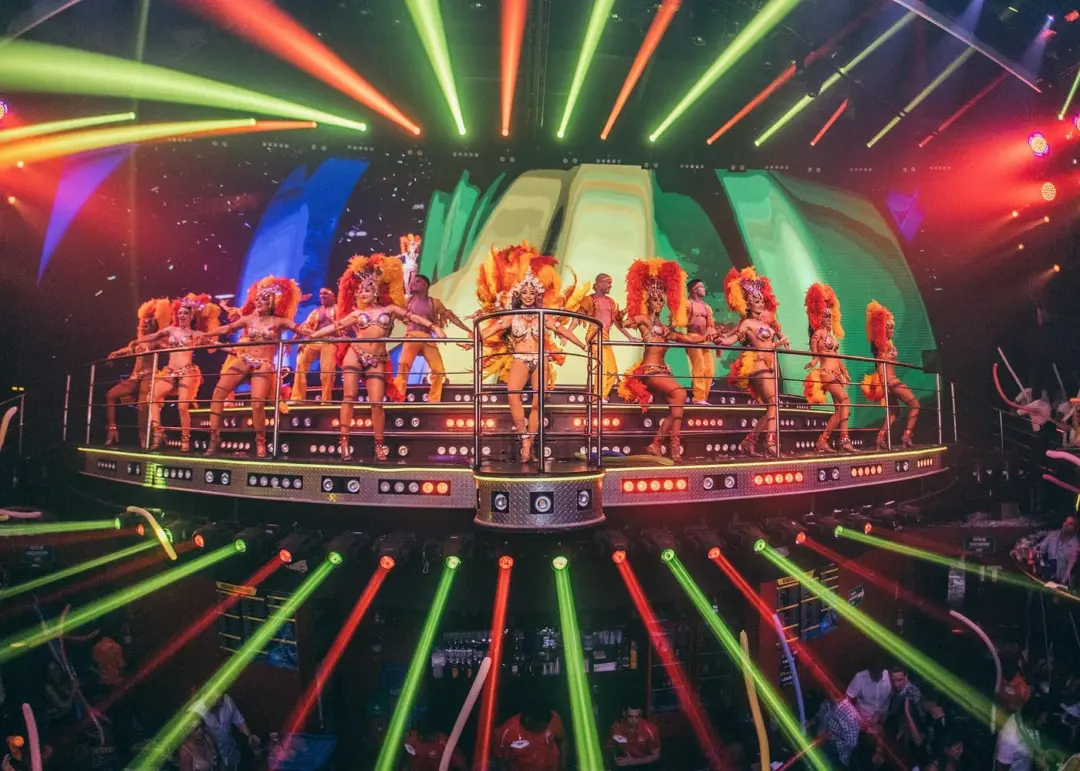 Performers in colorful costumes on Coco Bongo Cancun’s illuminated stage