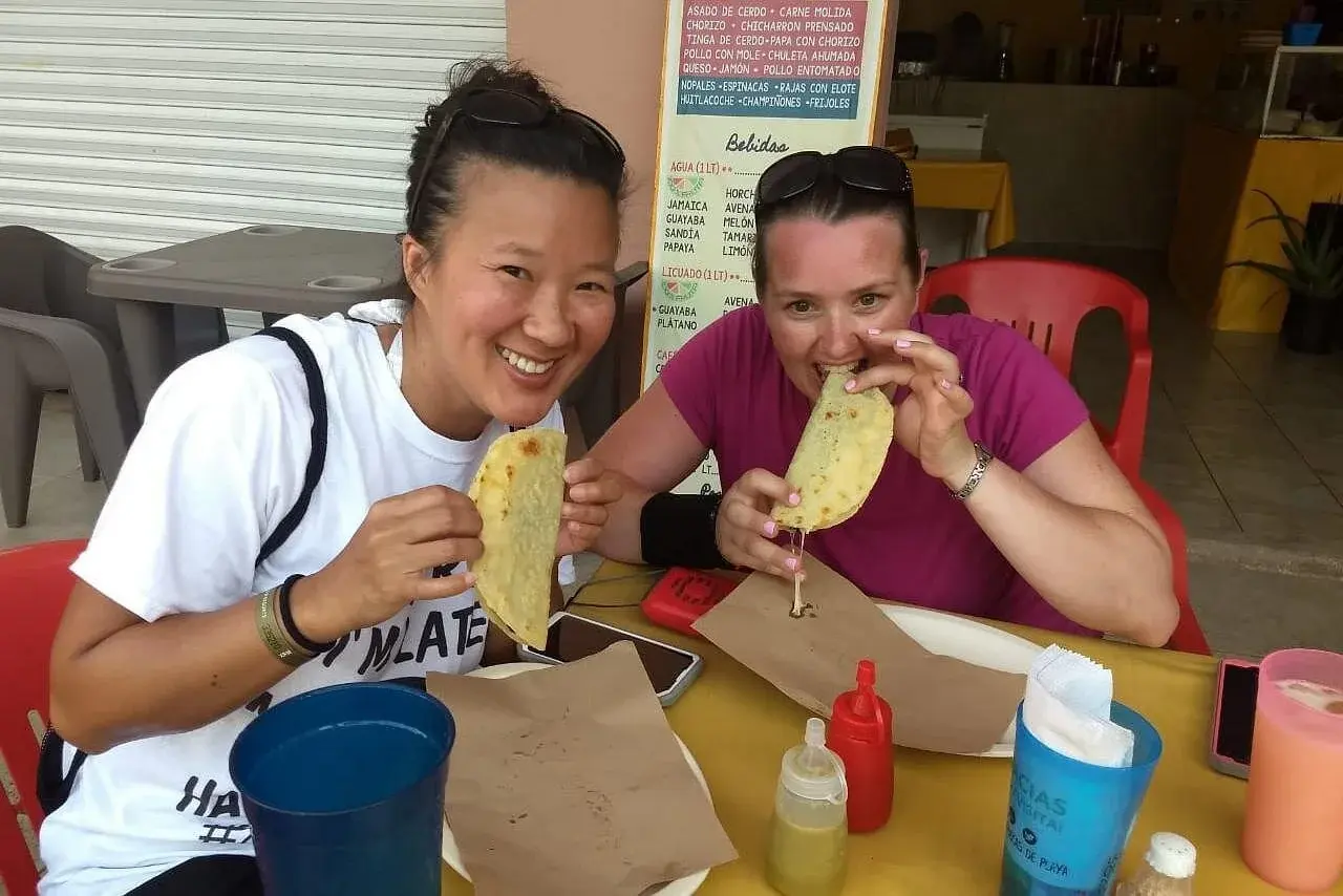 Two visitors tasting quesadillas at a local eatery on the Playa del Carmen food walk