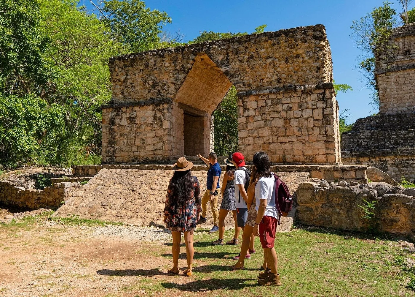 Guide and visitors beside the stone entrance arch at Ek Balam