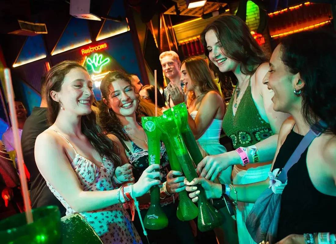 Guests raising green drinks together inside a Cancun nightlife venue