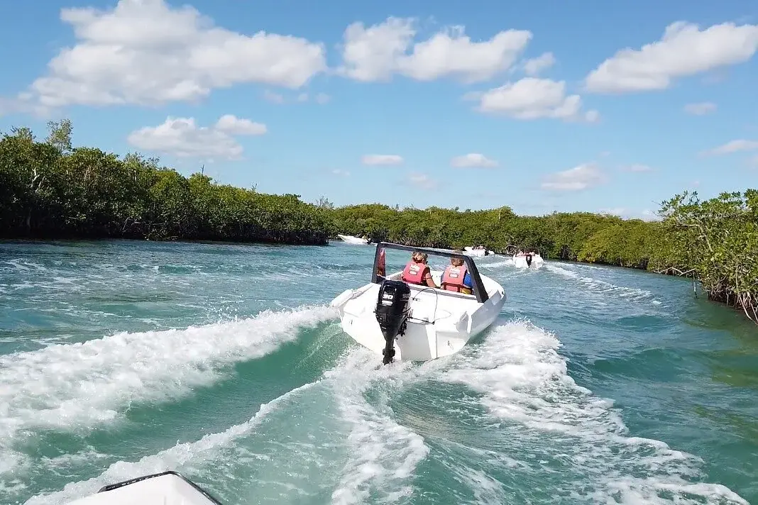 Visitors driving a speedboat through a mangrove channel in Nichupté Lagoon
