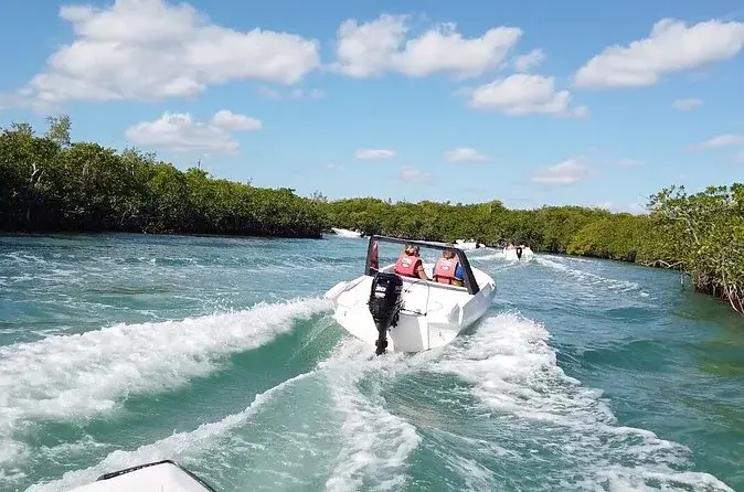 Visitors driving a speedboat through a mangrove channel in Nichupté Lagoon